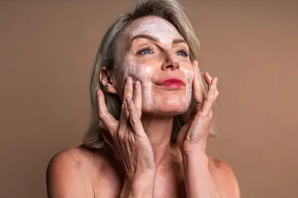 Dojrzała kobieta nakłada krem na twarz